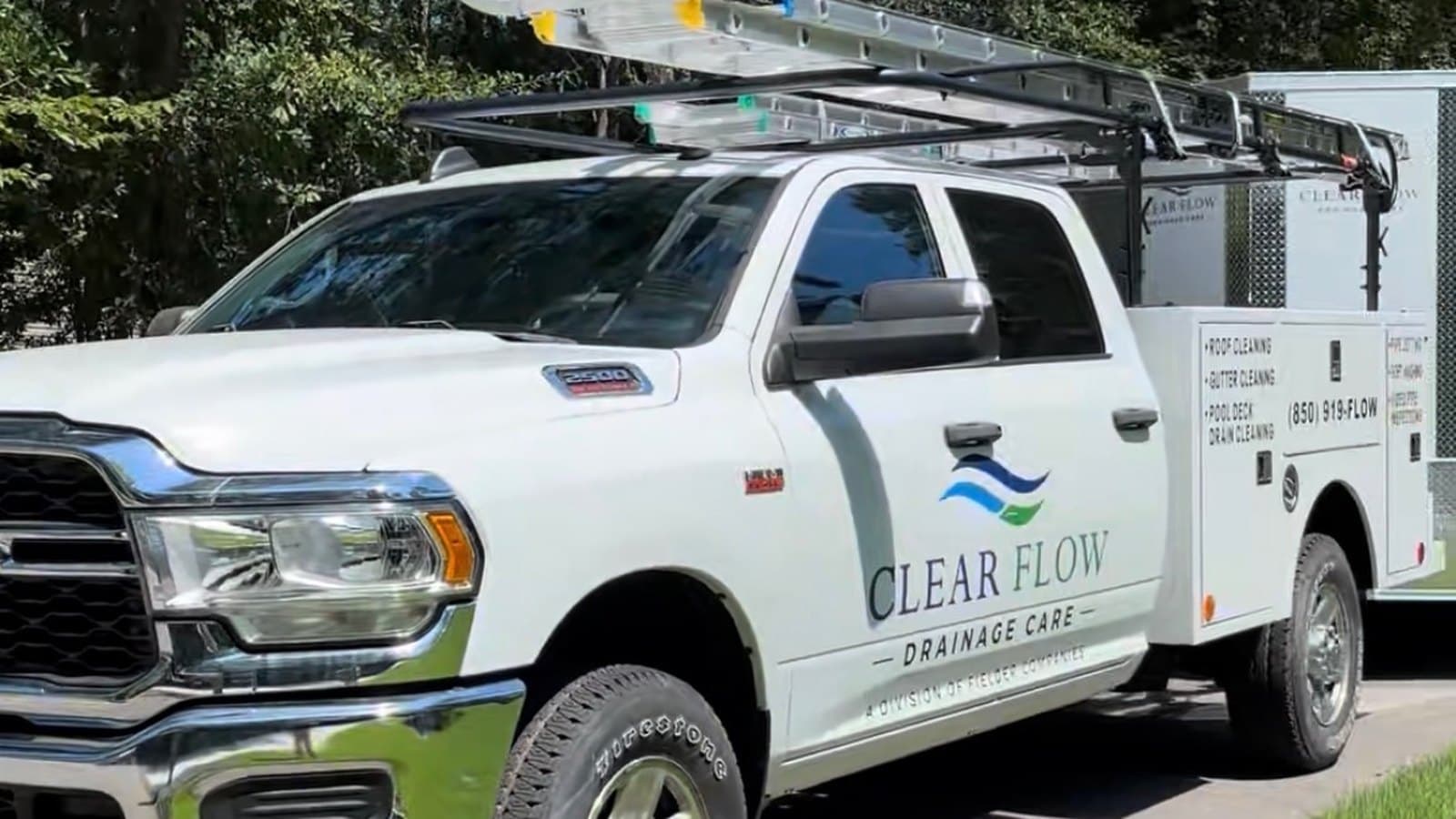 Clear Flow service truck at a job with the service list on the door and the ladder rack loaded